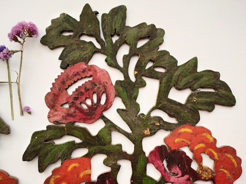 Peut inclure: Une d&eacute;coupe de papier d&eacute;corative repr&eacute;sentant un motif floral avec des fleurs rouges, roses et orange et des feuilles vertes. La d&eacute;coupe est peinte et a un aspect rustique et vintage.