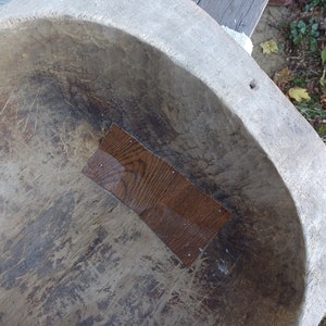 May include: A large, oval-shaped wooden bowl with a worn, gray surface. The bowl has a rectangular patch of wood on the inside, which is a darker brown color.