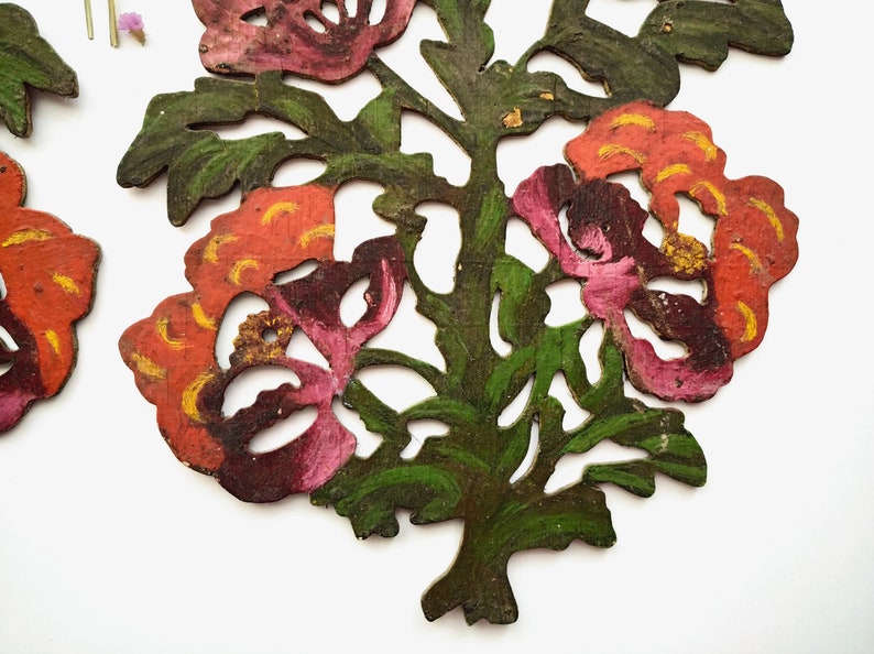Peut inclure: Deux d&eacute;corations florales en bois d&eacute;coup&eacute;es et peintes de mani&egrave;re complexe. Les fleurs sont un m&eacute;lange de rose, rouge et orange avec des accents jaunes. Les feuilles sont vertes et l'arri&egrave;re-plan est blanc.