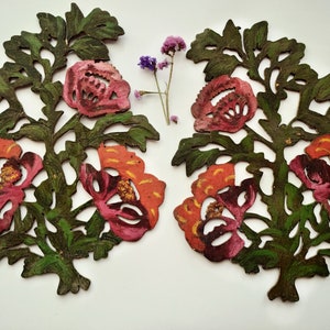 Peut inclure: Deux d&eacute;coupes de papier sym&eacute;triques de motifs floraux peints en rouge, orange et vert. Les d&eacute;coupes pr&eacute;sentent des fleurs stylis&eacute;es avec des d&eacute;tails complexes.