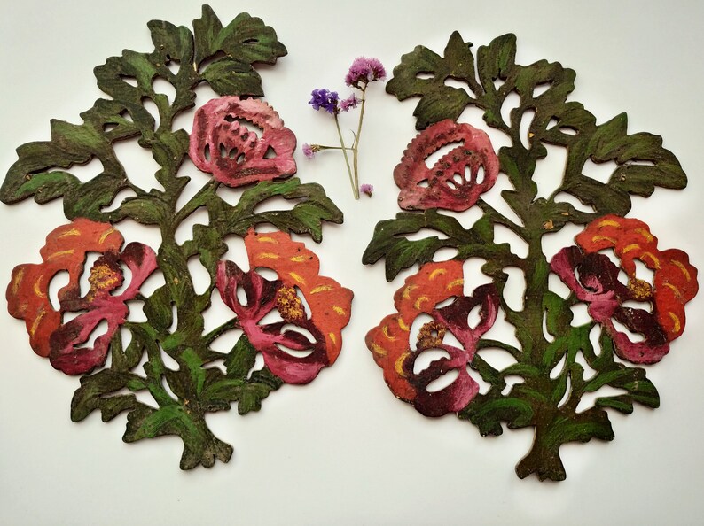 Peut inclure: Deux d&eacute;coupes de papier sym&eacute;triques de motifs floraux peints en rouge, orange et vert. Les d&eacute;coupes pr&eacute;sentent des fleurs stylis&eacute;es avec des d&eacute;tails complexes.