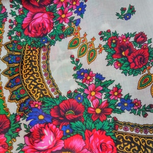 K&ouml;nnte beinhalten: Wei&szlig;er Stoff mit einem bunten Blumenmuster. Das Muster zeigt rote, rosa, blaue, gr&uuml;ne und gelbe Blumen. Der Stoff hat ein sich wiederholendes Muster aus verzierten goldenen und schwarzen Designs.