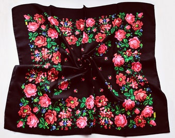 Könnte beinhalten: Ein schwarzer quadratischer Schal mit einem Blumenmuster aus roten, rosa und grünen Rosen. Der Schal ist in der Mitte gefaltet und hat eine strukturierte Oberfläche.