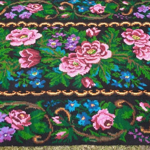 May include: A traditional Romanian rug with a floral pattern. The rug is woven with wool and features a black background with pink, red, blue, and green flowers.