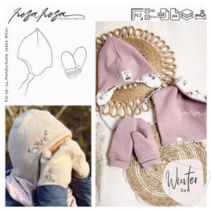 Könnte beinhalten: Eine rosafarbene Wintermütze, passende Fäustlinge und ein rosafarbener Schal mit weißem Blumenmuster. Die Mütze hat ein kleines weißes Etikett mit dem Text "Klein und Oho". Das Set wird auf einer geflochtenen Strohmatte mit dem Text "Winter Set" präsentiert.