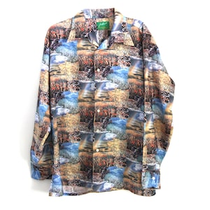 May include: Long-sleeved button-down shirt with a landscape pattern in shades of blue, brown, and beige. The shirt has a classic collar and buttoned cuffs. A green tag is visible near the collar.