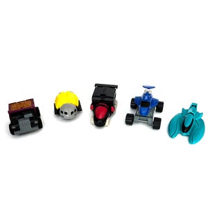 Puede incluir: Cinco vehículos de juguete coloridos están dispuestos sobre una superficie blanca. Los juguetes incluyen un camión morado y negro, un coche amarillo y plateado, un coche negro y rojo, un coche de carreras azul y un vehículo futurista turquesa.