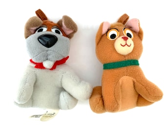 May include: Two plush animal toys: a dog and a cat. The dog has a gray face, brown ears, and a red collar. The cat is brown with a green collar. Both toys are sitting upright and have a soft, plush texture.