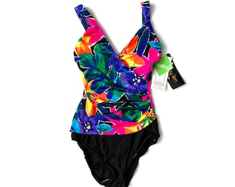 Puede incluir: Un traje de baño negro con estampado floral de colores. El traje de baño tiene un escote en V y tirantes ajustables. La etiqueta dice "Bustline by Ellen".