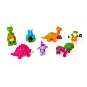 Può includere: Una collezione di figurine di plastica colorate, tra cui dinosauri e altre creature. Le figurine sono in vari colori, come verde, arancione, rosa e viola. Alcune figurine hanno la lettera "M".