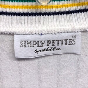 Pode incluir: Etiqueta branca com o texto "SIMPLY PETITES by cricket love" em letras pretas com um s&iacute;mbolo de marca registrada.