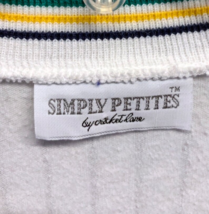 Pode incluir: Etiqueta branca com o texto "SIMPLY PETITES by cricket love" em letras pretas com um s&iacute;mbolo de marca registrada.