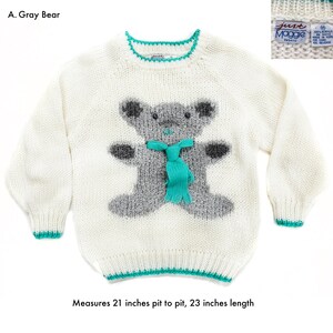 Pode incluir: Um su&eacute;ter branco com um desenho de urso cinzento, um cachecol turquesa e acabamentos turquesa. O su&eacute;ter mede 53 cm de axila a axila e 58 cm de comprimento. O texto "A. Gray Bear" &eacute; vis&iacute;vel.