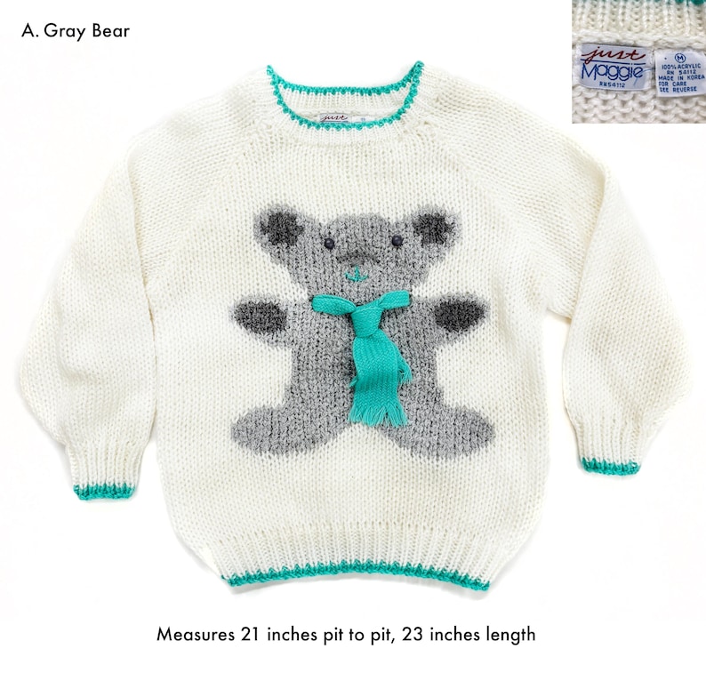 Pode incluir: Um su&eacute;ter branco com um desenho de urso cinzento, um cachecol turquesa e acabamentos turquesa. O su&eacute;ter mede 53 cm de axila a axila e 58 cm de comprimento. O texto "A. Gray Bear" &eacute; vis&iacute;vel.