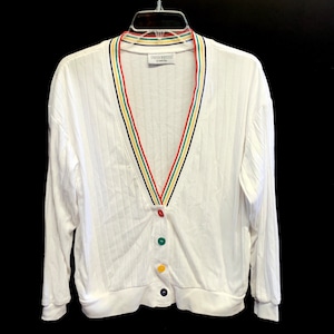 Pode incluir: Cardigan branco com gola listrada em vermelho, amarelo, verde e azul. O cardigan tem um decote em V e quatro bot&otilde;es coloridos.