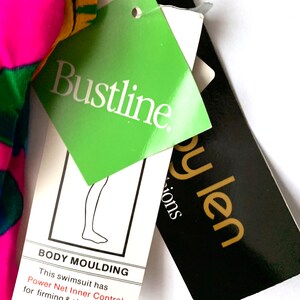 May include: A green and white tag with the text "Bustline." and the text "BODY MOULDING This swimsuit has Power Net Inner Control for firming & shaping action."  A black tag with gold text reads "py len Sions".