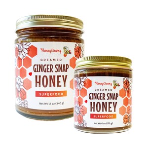 May include: Two glass jars of creamed ginger snap honey. The smaller jar is 6 ounces and the larger jar is 12 ounces. Both jars have a gold lid and a label with a honeycomb pattern and a cartoon bee.