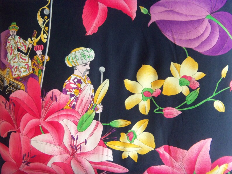 May include: A dark blue fabric with a colorful floral pattern. The pattern includes pink, yellow, and purple flowers, as well as three figures in traditional clothing.