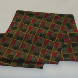 May include: A long green, red, and gold patterned scarf with a paisley design.