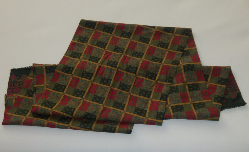 May include: A long green, red, and gold patterned scarf with a paisley design.