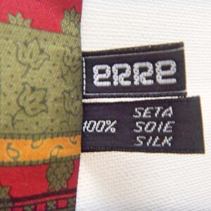 May include: A black and white label with the text "2222" and "SETA SOIE SILK 100%" on a red, green, and yellow patterned fabric.