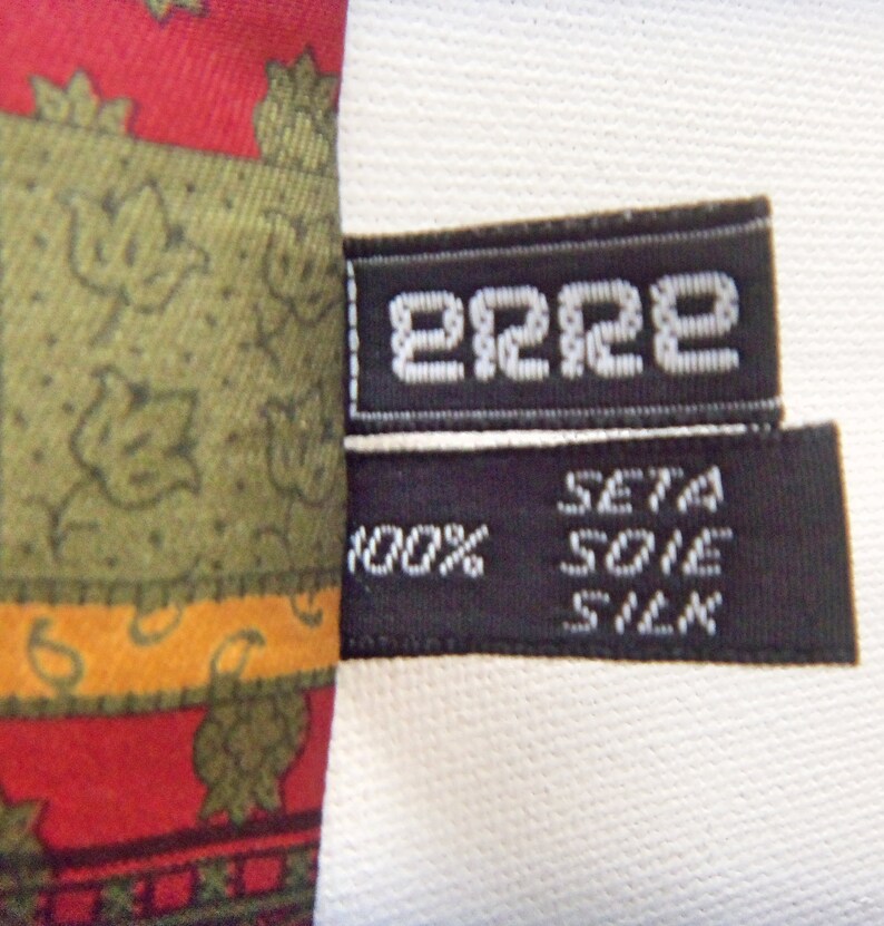 May include: A black and white label with the text "2222" and "SETA SOIE SILK 100%" on a red, green, and yellow patterned fabric.