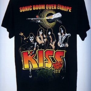 K&ouml;nnte beinhalten: Schwarzes T-Shirt mit einem Grafikdruck der Band KISS vor einem Flugzeug mit dem Text "Sonic Boom Over Europe" und "Sonic Boom Tour 2010".