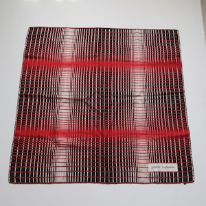 Pode incluir: Um lenço de seda com padrão preto e vermelho com uma etiqueta branca que diz "pierre balmain".