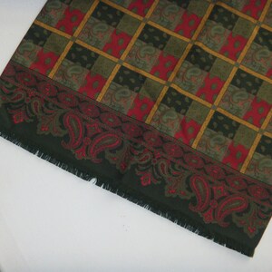 May include: A green and red paisley patterned scarf with a fringed edge.