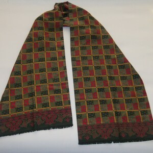 May include: A green, red, and gold patterned scarf with a fringed edge.