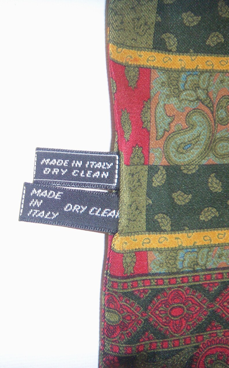 May include: Two black fabric tags with white stitching and text. The top tag reads "Made in Italy Dry Clean". The bottom tag reads "Made in Italy Dry Clean".