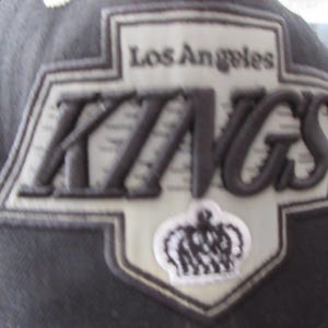 Puede incluir: Una gorra de béisbol negra y blanca con un gran parche bordado con las palabras "Los Angeles Kings" y una corona.