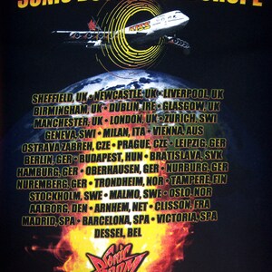 K&ouml;nnte beinhalten: Ein schwarzes T-Shirt mit einem Grafikdruck eines Flugzeugs, das durch einen Feuerring fliegt. Der Text "Sonic Boom Over Europe" befindet sich oben auf dem Shirt. Der Text "Tour 2010" befindet sich unten auf dem Shirt.