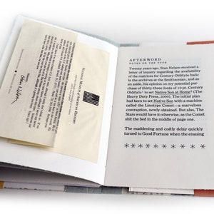 May include: A close-up of an open book with a white background and a red and orange border. The text on the page reads "AFTERWORD NOTES ON THE TYPE" and continues with a story about the process of setting type for a book. The book is titled "Native Son at Home".