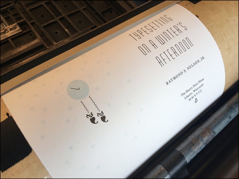 May include: A white book cover with the title "Typesetting on a Winter's Afternoon" by Raymond S. Nelson, Jr. The cover features a simple illustration of a clock with two black hearts hanging from it. The book is published by The Heavy Duty Press in Liberty, Wisconsin.