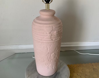 May include: A pink ceramic table lamp with a textured surface and a gold metal lampshade. The lamp is on a white marble base.