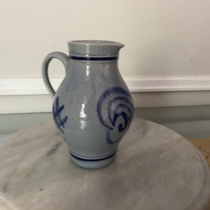 May include: A blue and white ceramic jug with a blue swirl design. The jug has a handle and a spout.