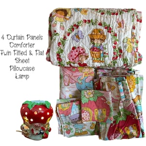 May include: A Strawberry Shortcake themed bedding set with a comforter, twin fitted and flat sheet, pillowcase, and lamp. The set features a white background with red strawberries, green leaves, and images of Strawberry Shortcake and her friends.