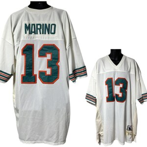 May include: White mesh jersey with the name "MARINO" and the number "13" in teal and orange. The jersey has teal and orange stripes on the sleeves. The jersey is displayed on a black mannequin.