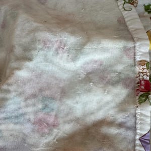 May include: Close-up of a white fabric with a floral pattern. The fabric has a textured surface and appears to be slightly wrinkled.