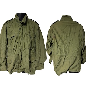 May include: Olive green military-style jacket with multiple front pockets and a high collar. The jacket has a button-up front and epaulets on the shoulders. The back of the jacket has the word "SPECIMEN" printed on it.