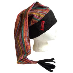 May include: A colorful striped hat with a long, pointed end and a black brim. The hat features a red rectangular patch with the text "RULA". The hat is displayed on a white mannequin head.