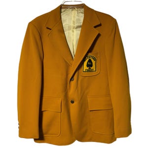 Puede incluir: Una chaqueta de color amarillo mostaza con un parche en el pecho izquierdo que dice "Allentown Forest 61".