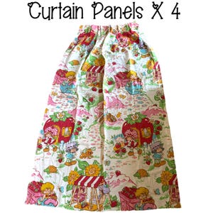 May include: A set of four white cotton curtain panels featuring a Strawberry Shortcake print. The panels have a pink, red, and green floral pattern with cartoon characters and a strawberry motif. The text "Curtain Panels x 4" is printed at the top of the image.