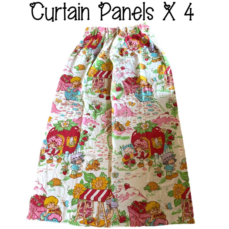 May include: A set of four white cotton curtain panels featuring a Strawberry Shortcake print. The panels have a pink, red, and green floral pattern with cartoon characters and a strawberry motif. The text "Curtain Panels x 4" is printed at the top of the image.