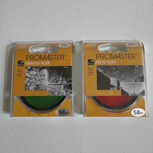 May include: Two Promaster camera filters: a green P01 filter and a red R2 filter, both 58mm. The filters are in clear plastic packaging with yellow and black labels. The green filter shows a black and white image of a woman. The red filter shows a black and white image of a building.