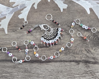 May include: A set of ten colorful stitch markers with numbers 1 through 10. The markers are made of metal rings with colorful beads and white numbers. The markers are strung together on a silver chain.