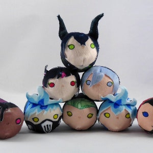 May include: A group of eight plush toys, each with a different character design. The toys are arranged in a pyramid shape, with the largest toy at the top and the smallest toys at the bottom. The toys are all made of soft, plush fabric and have embroidered details. The characters include a green-skinned creature with horns, a black-haired character with red eyes, a blue-haired character with blue eyes, a green-skinned character with yellow eyes, a blue-haired character with yellow eyes, a black-haired character with yellow eyes, a brown-skinned character with pink eyes, and a red-skinned character with blue eyes.