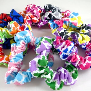 May include: A collection of colorful scrunchies with a geometric pattern. The scrunchies are made of fabric and have a white background with different colored geometric shapes.