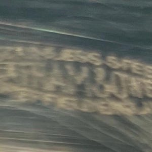 May include: Blurred image of text that reads "STAINLESS STEEL GRAY RAVEN JEWELERS ENGLAND". The text is in a light color against a darker background.